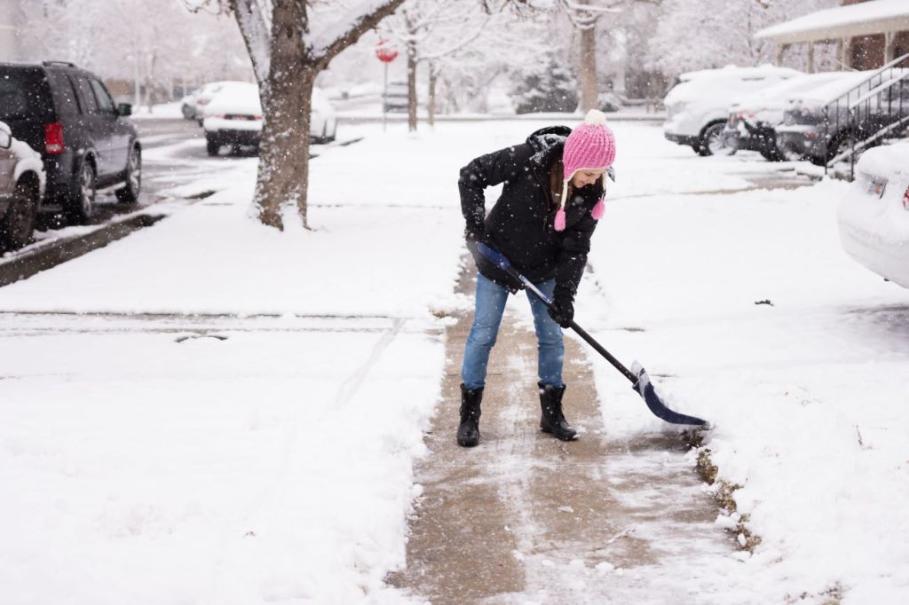 A young teenager shovelling the sidewalk