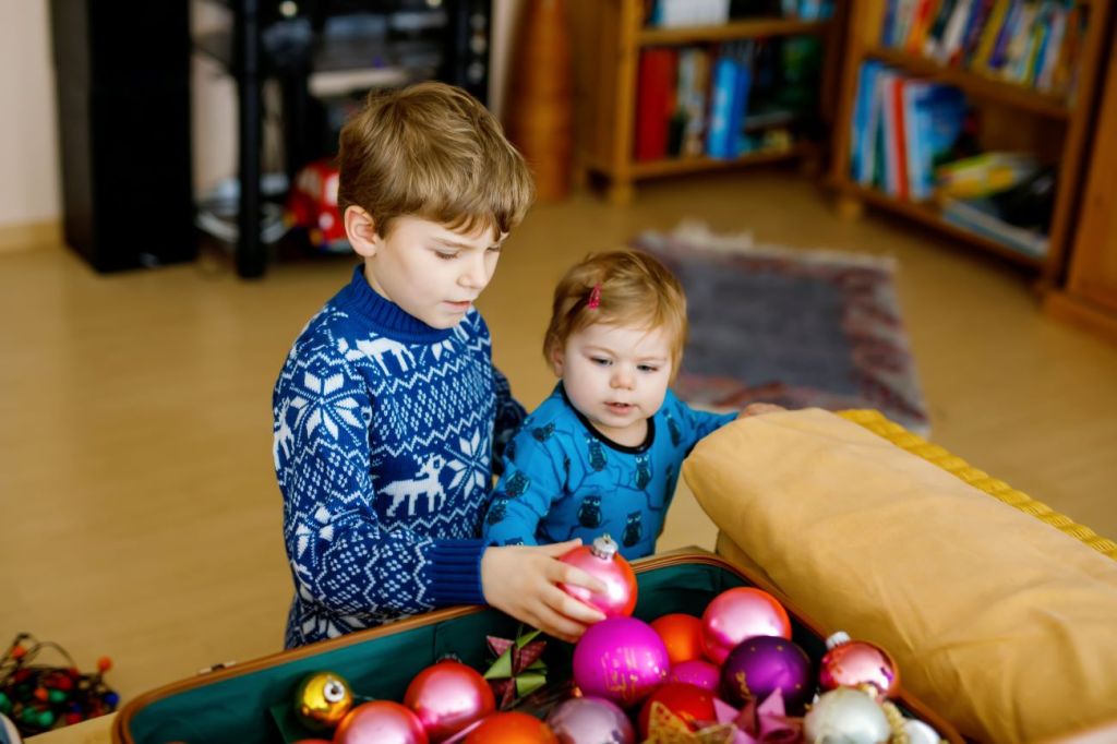 Two young kids putting away Christmas decorations