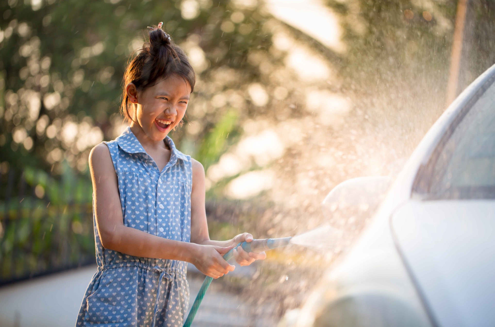 A young girl washing her parents car for allowance