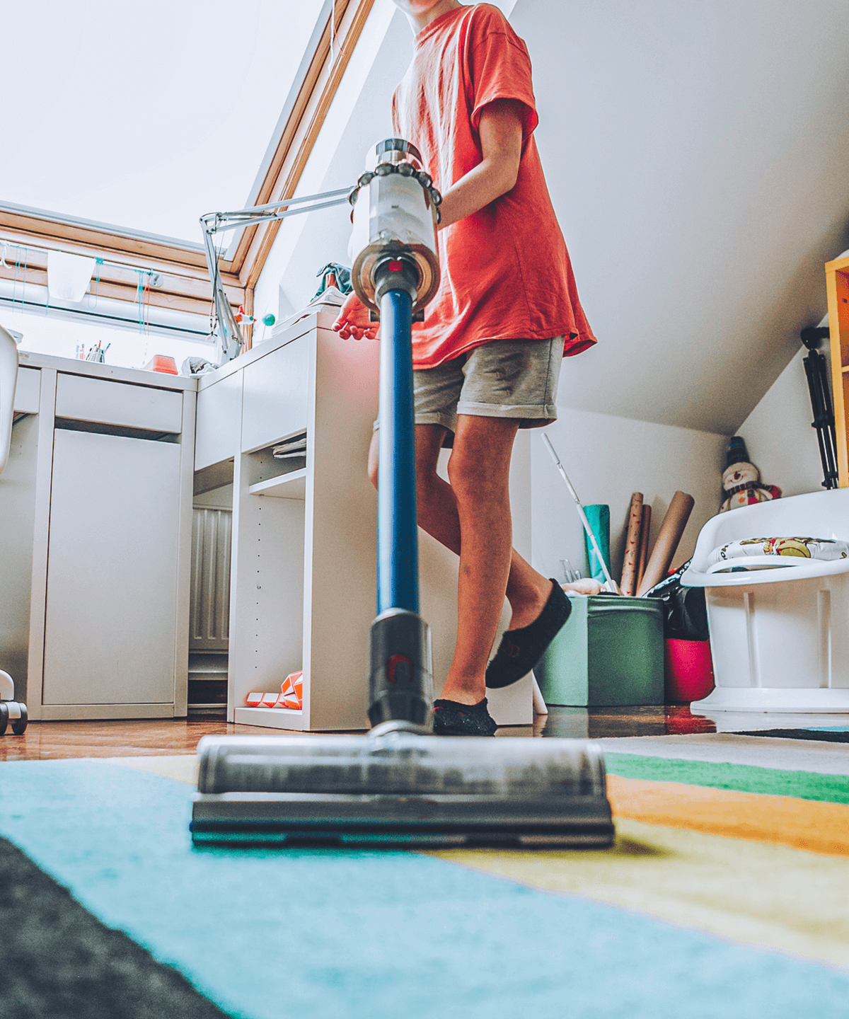 A teenager vacuuming his room with a Dyson vacuum