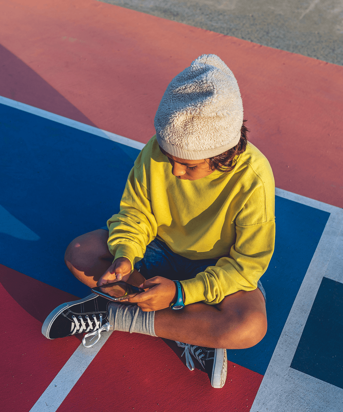 A boy sitting outdoors using the Mydoh app on his mobile phone