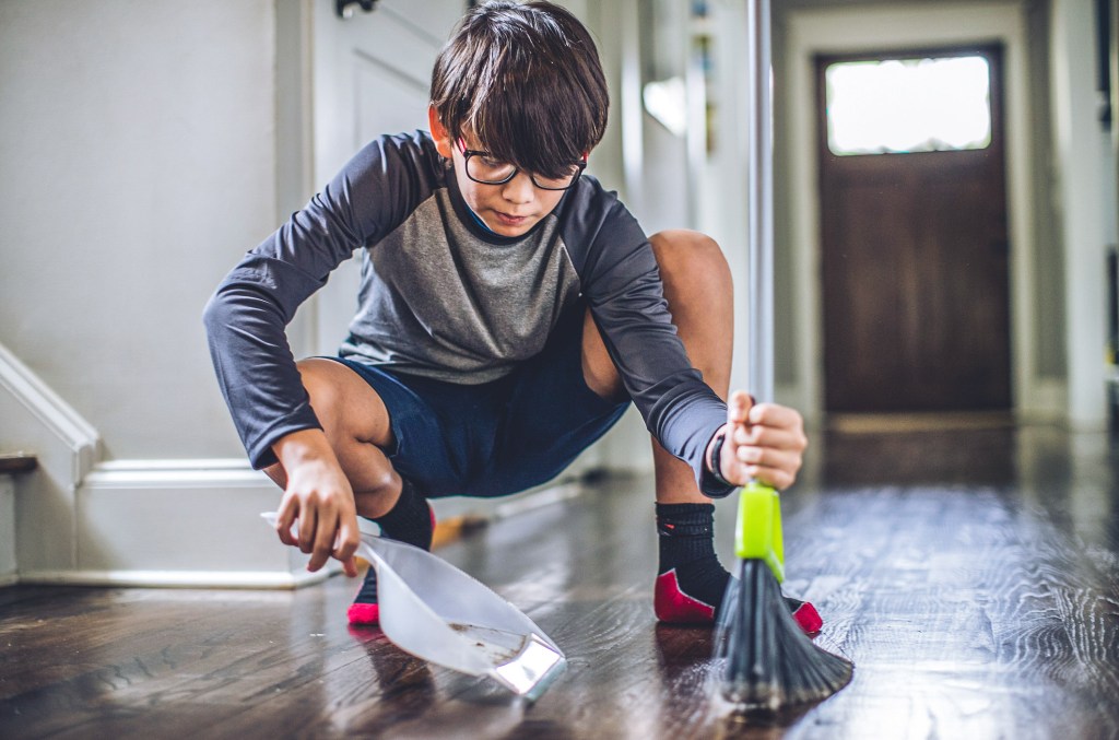 A young boy doing his chores and sweeping the floor