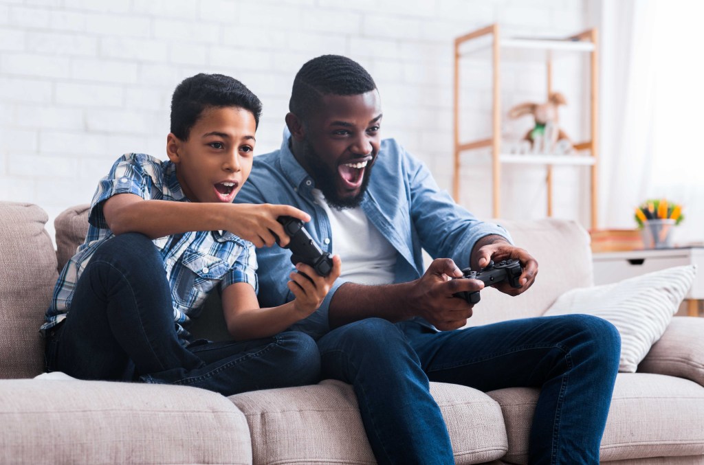 Father and son playing video games on a couch