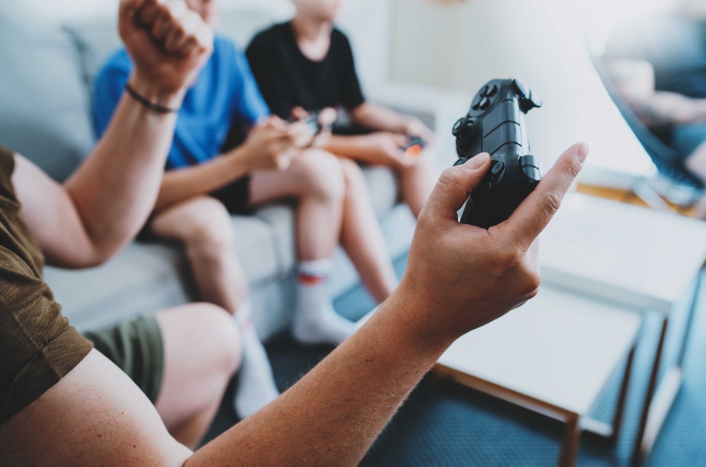 A teen holding playstation controller and gaming with friends