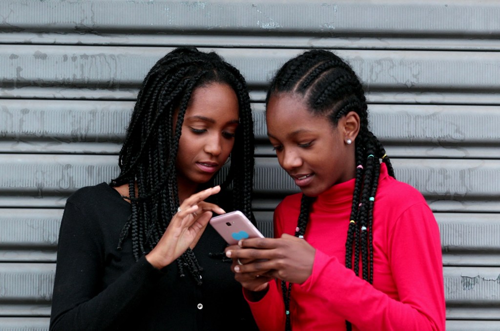 Two young girls looking at social media accounts on a phone
