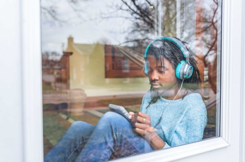 teen wearing headphones looking at phone