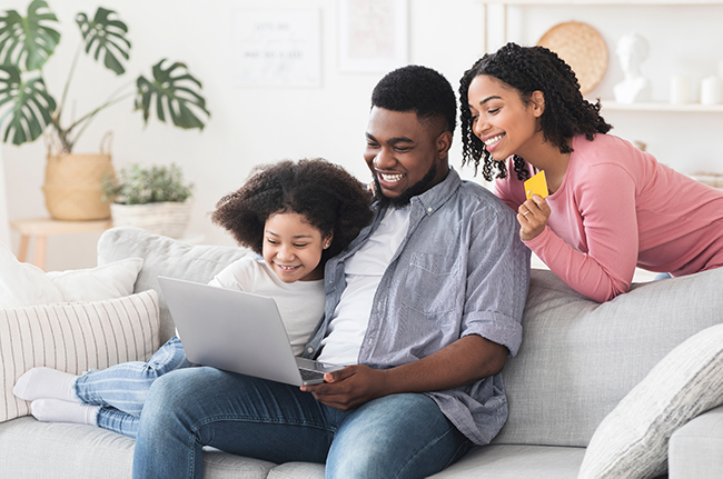 A father teaching his young daughters how to use a credit card online