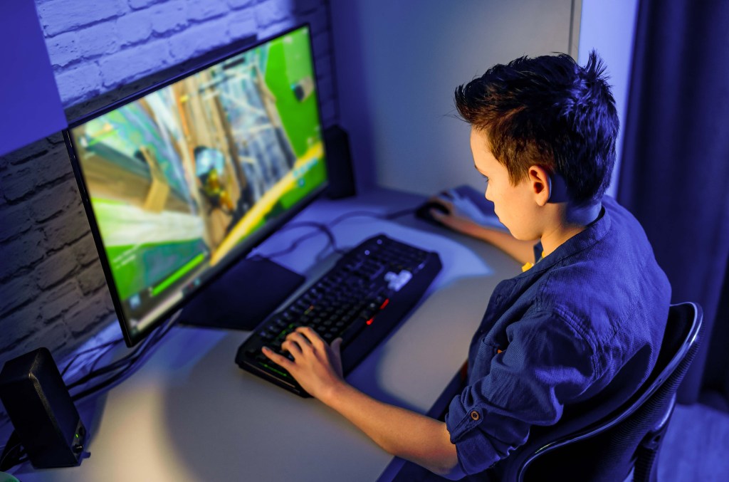 A teen boy playing an online game on his PC