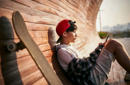 teen boy with skateboard on phone