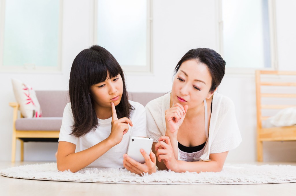 A mother and daughter looking at a Twitter feed together on a phone