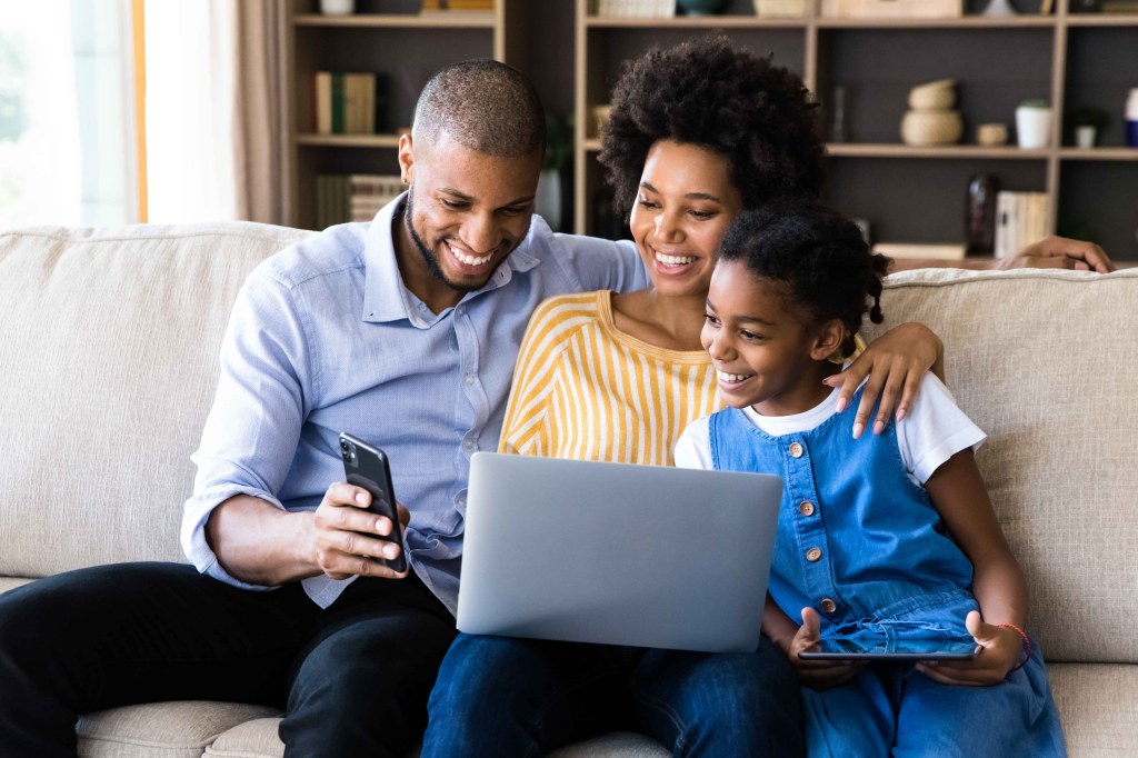 A mother and father teaching their daughter about budgeting on a phone