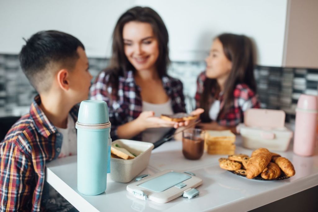 woman making packed lunch for son and daughter to save money