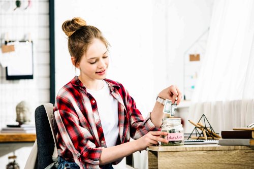 Teenager in checkered shirt putting money in the piggy bank