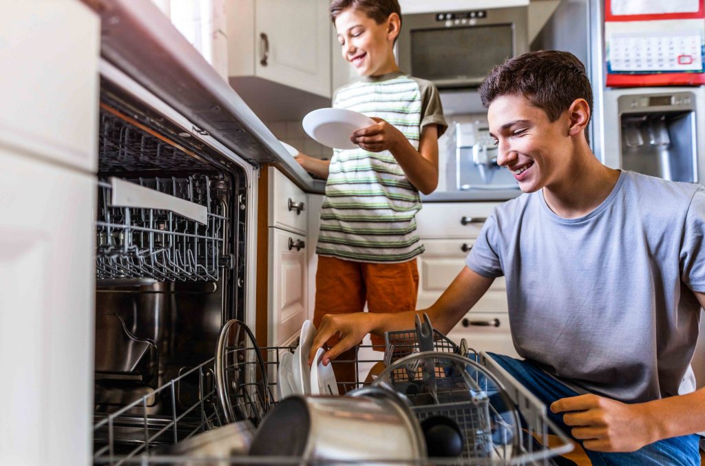 Two boys loading the dishwasher together at home