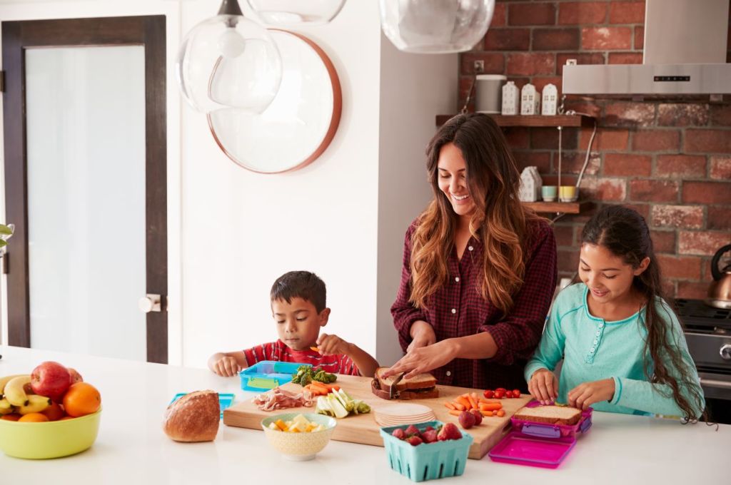 Boy, woman, and girl stand at kitchen counter making lunch