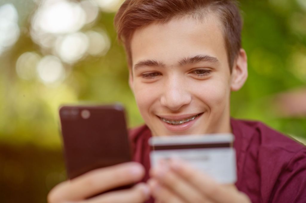 A young boy entering a credit card on his phone to buy something online