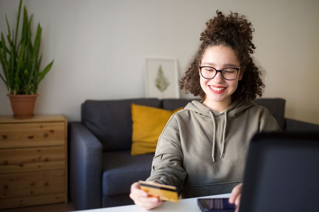 A young teen girl holding a credit card