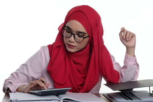 Girl wearing red hijab and glasses using a calculator