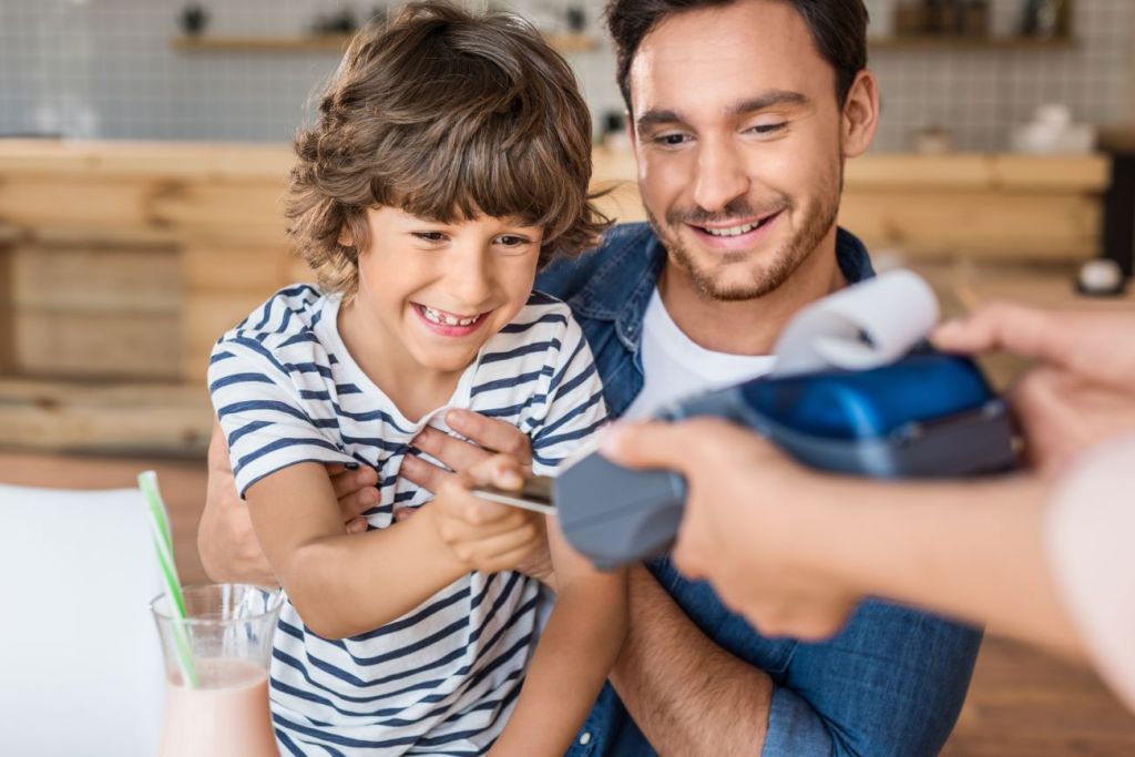 A father teaching his son how to use a credit card to pay for food A father teaching his son how to use a credit card to pay for food