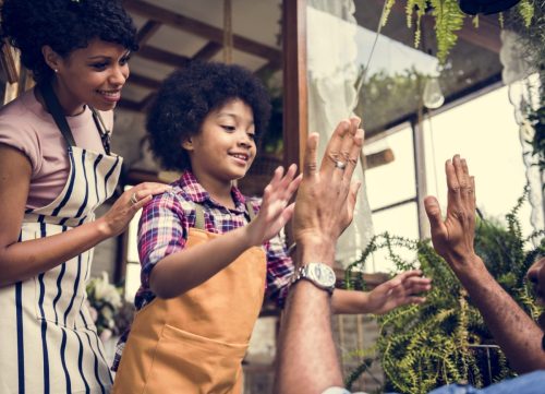 Kid wearing apron high fives person in front of them