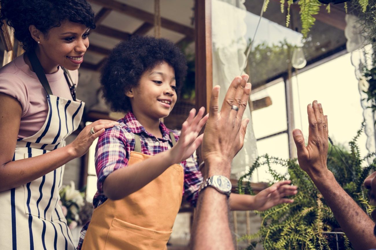 Kid wearing apron high fives person in front of them