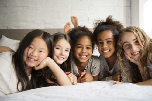 Group of girls lying on a bed smiling