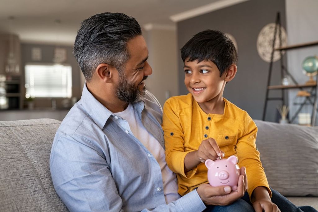 A father teaching his son to save with a piggy bank