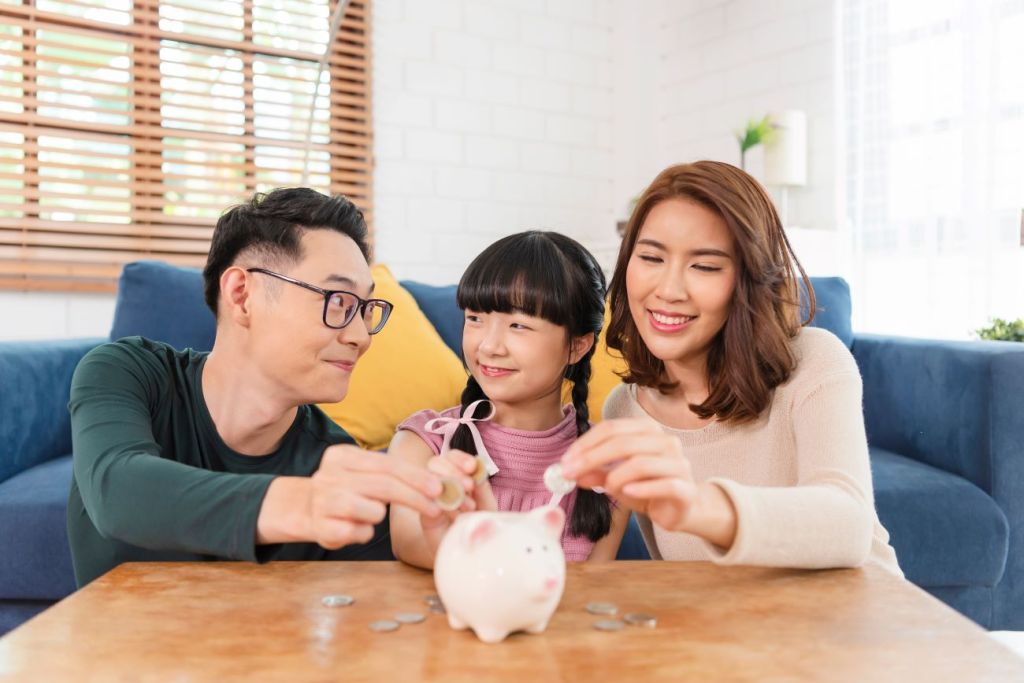 Parents and a young child investing money in a piggy bank together