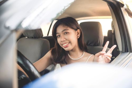 Smiling teen girl makes peace sign while sitting in her car