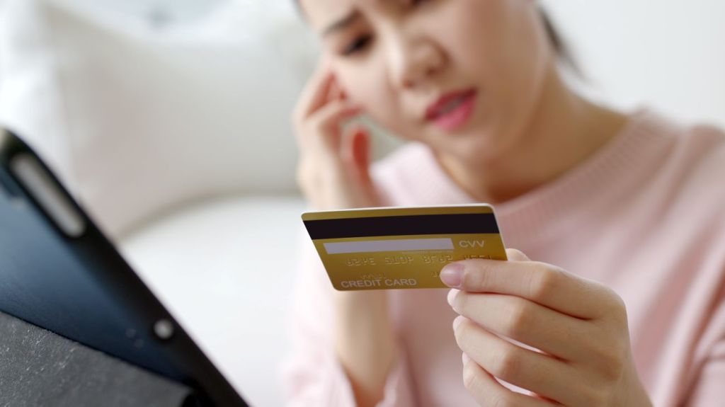 A teen girl holds credit card looking worried about debt