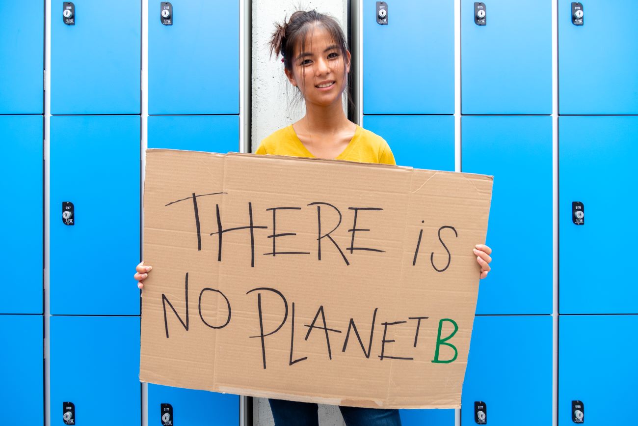 Teen Asian girl holds up "There is no Planet B" sign protesting climate change