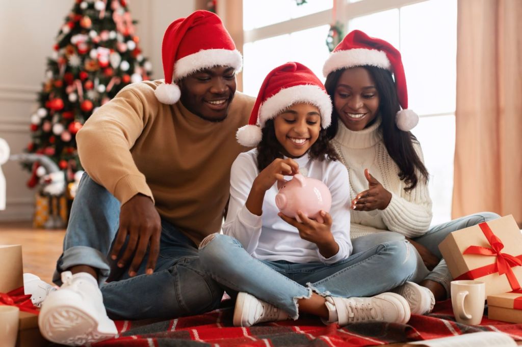 A young girl with her parents putting money in her piggy bank for Christmas