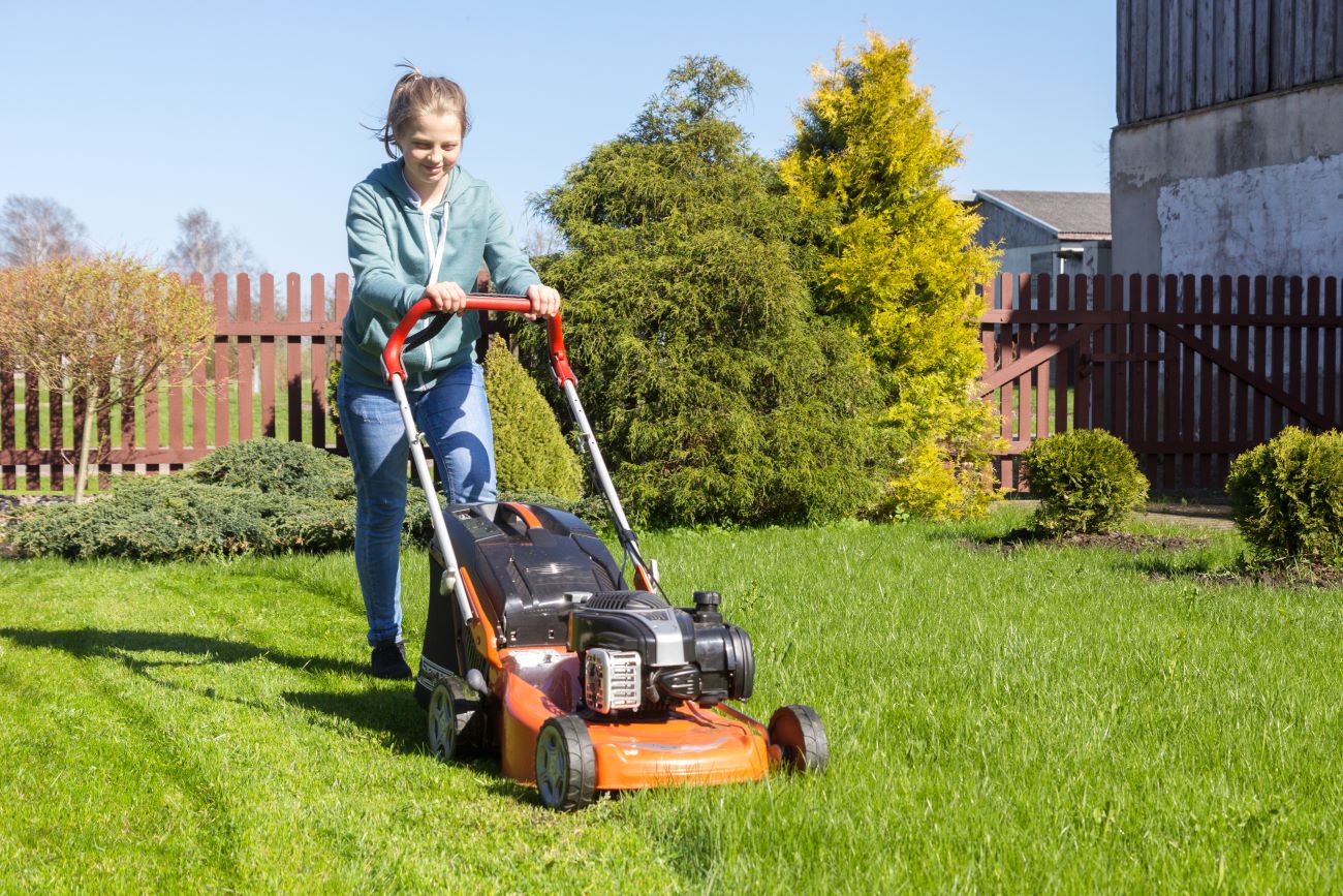 Teen girl doing chore of mowing the lawn