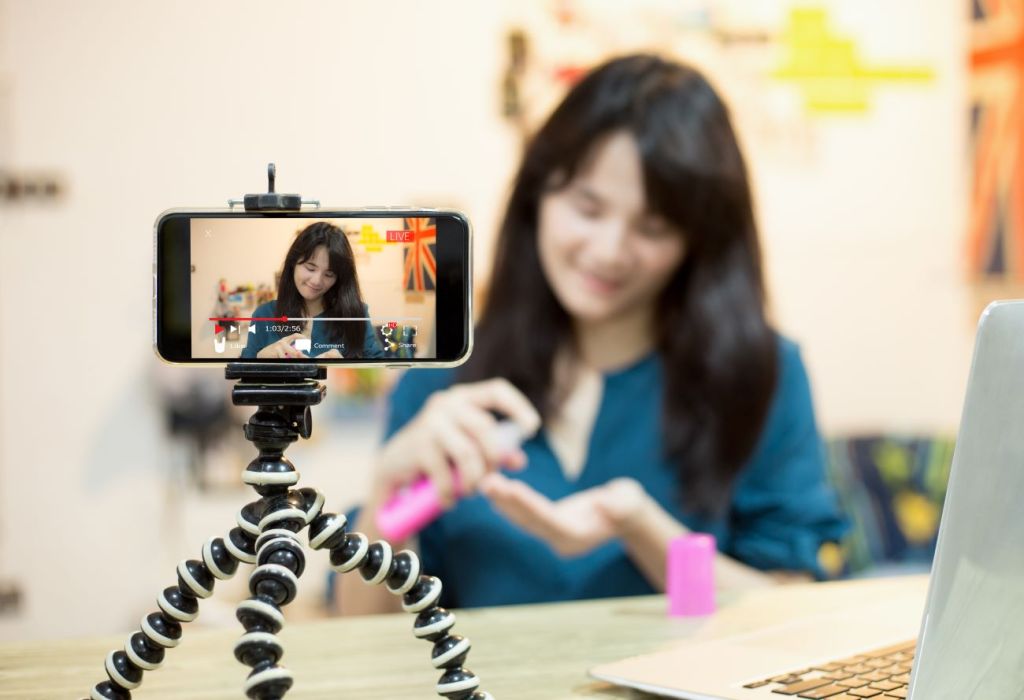 Teenage girl sits behind a camera making a YouTube video