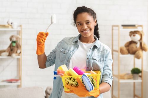 Teen girl holding cleaning brush and supplies ready to do chores