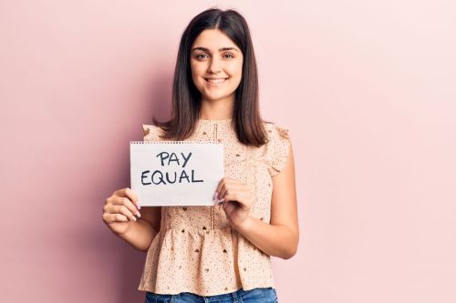 Smiling teen girl supports closing wage gap by holding up sign saying pay equal
