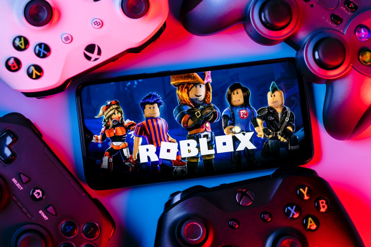 Roblox video game on smart phone surrounded by gaming devices