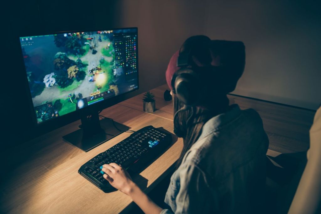 Teen playing multiplayer game on a computer with headphones