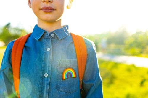 Child wearing denim shirt with LGBTQ2S+ rainbow