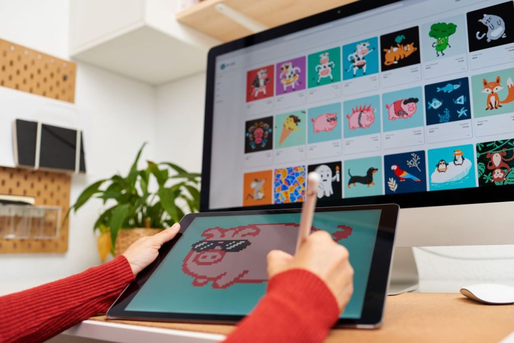 A child creating an NFT on iPad of pig wearing sunglasses with computer screen in background