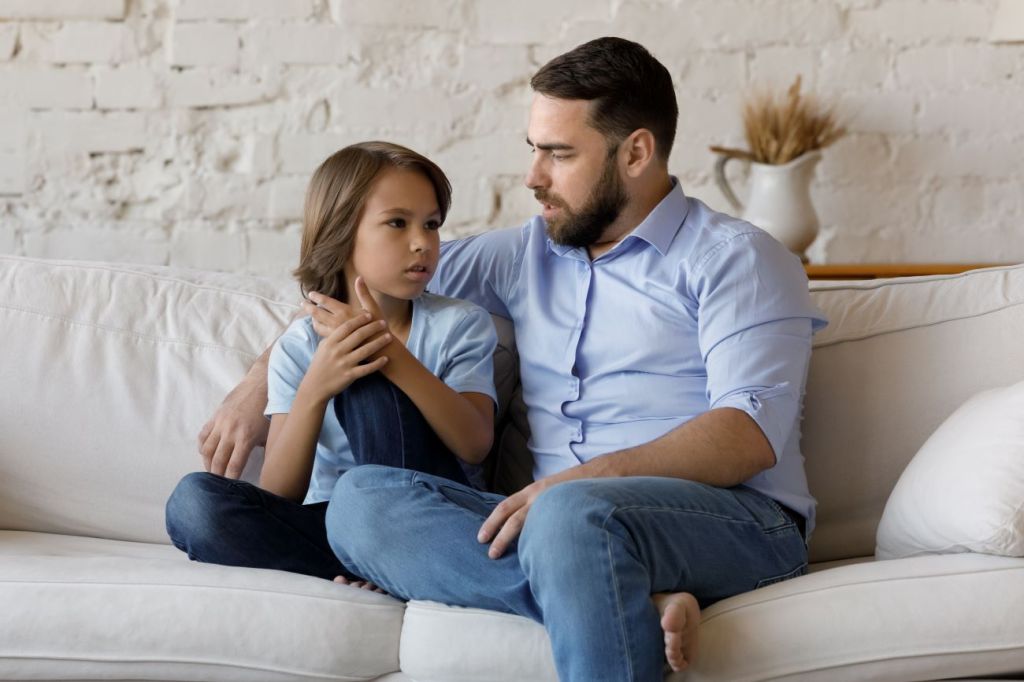 Man talks to boy on white couch about mental wellness