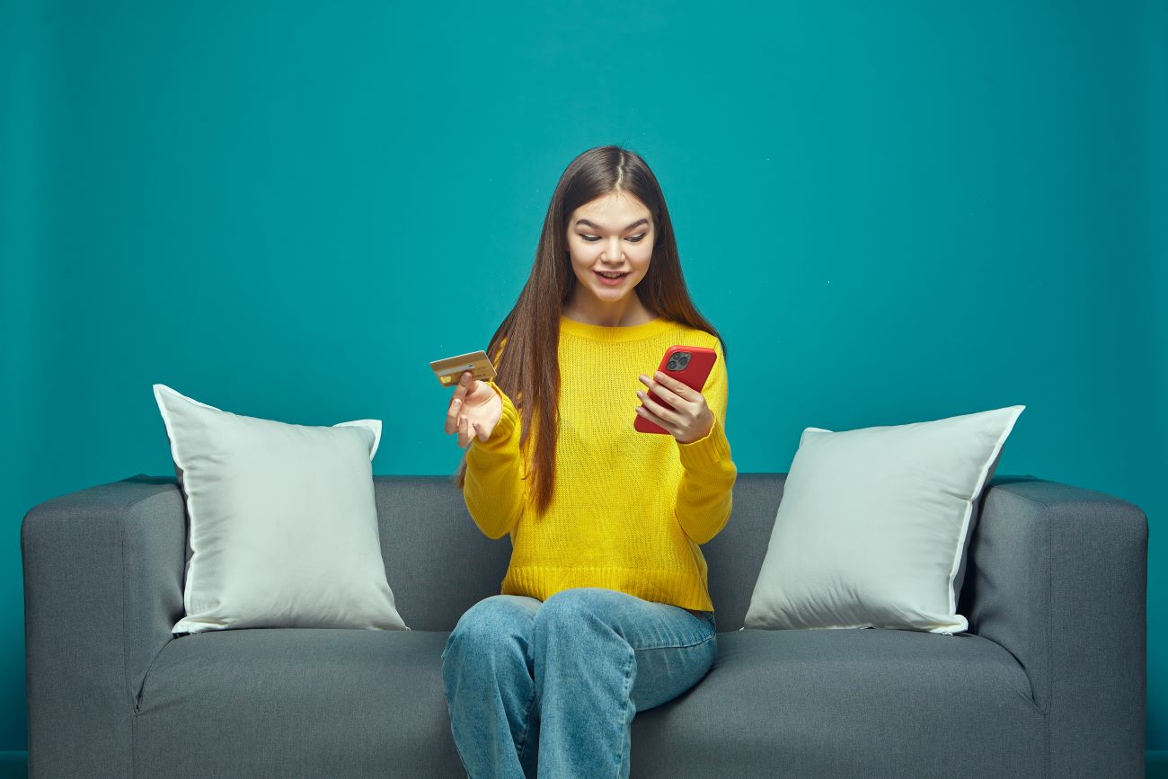 Girl holds bank card in one hand and phone in other