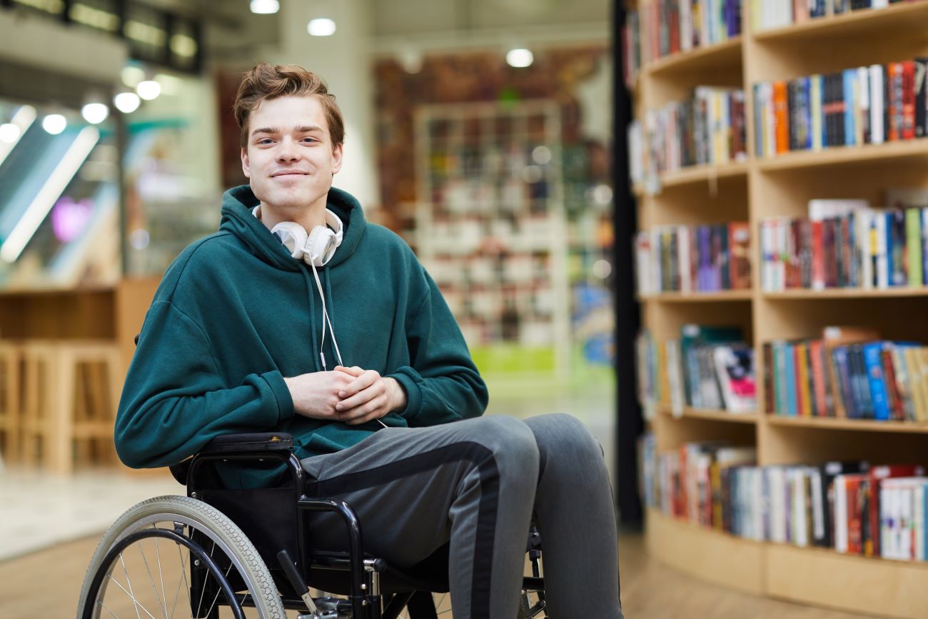 Male university student in wheelchair at school library