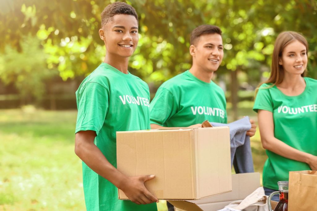 Group of three teens wearing green t-shirts that says "volunteer"