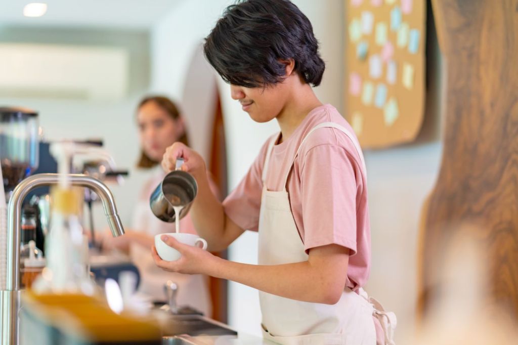 A teenager working part-time as a barista in a coffee shop