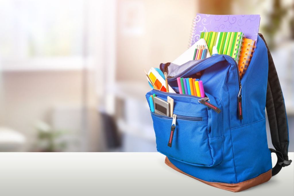 blue backpack with school supplies for middle school on desk