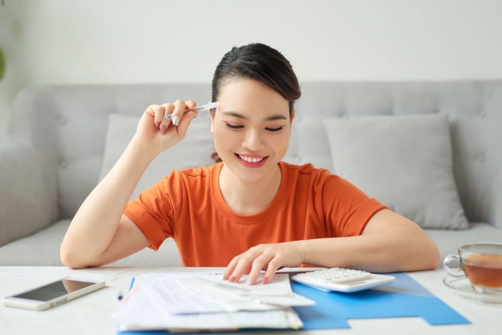 girl sits at table with bank finances smiling paying her debt