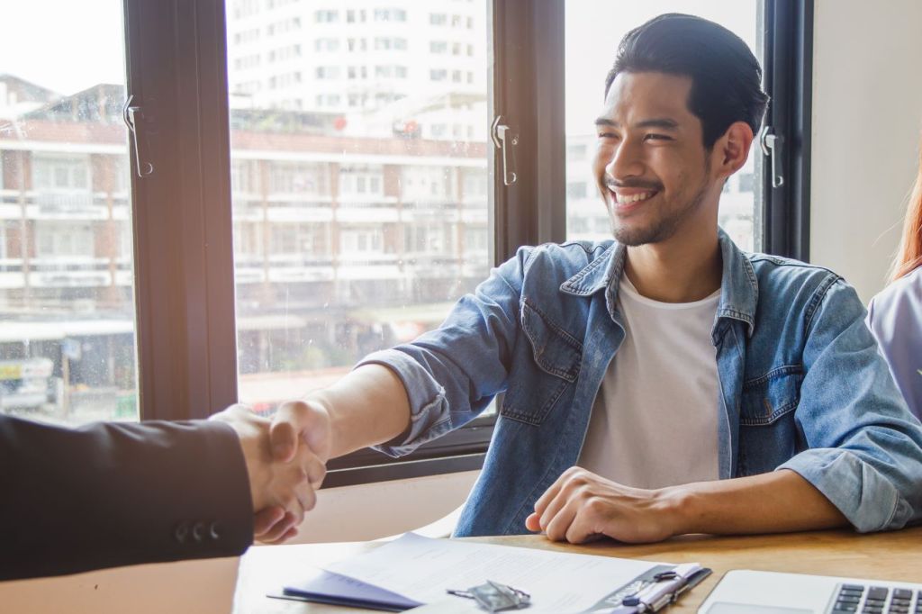 Smiling young man shaking someone's hand getting bank loan