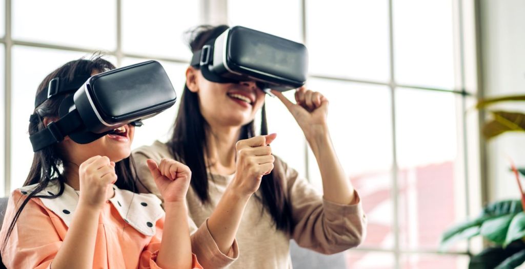 Asian woman and girl wearing VR headsets exploring metaverse