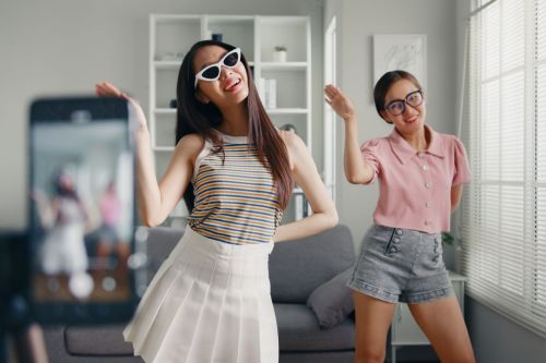 Two teen girls smiling and filming TikTok dance